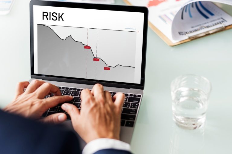 Gráfico de riesgo en una laptop, mostrando una tendencia a la baja. Persona escribiendo.