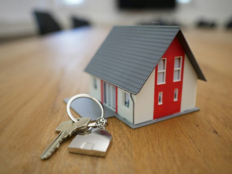 Casa de juguete con llaves sobre una mesa de madera.
