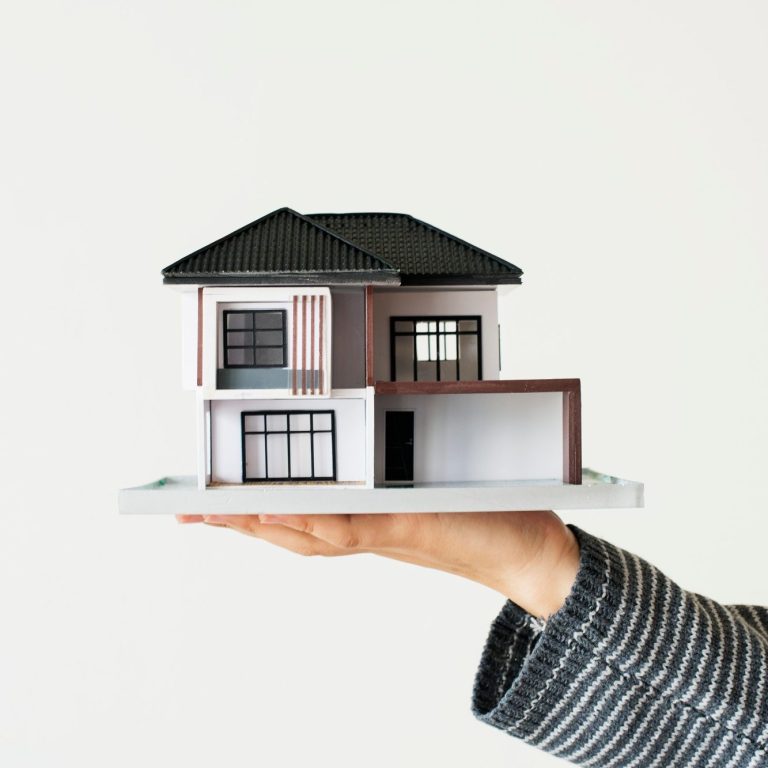 Maqueta de una casa moderna sostenida con una mano.