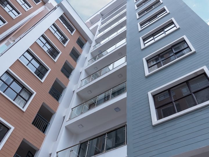 Edificio moderno con varios pisos y balcones, en tonos gris y naranja.